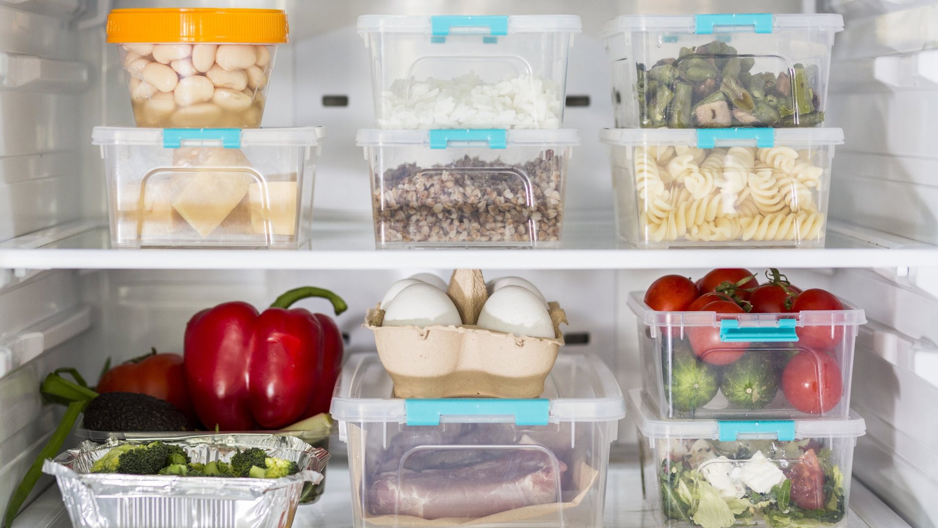 Продукты на полках холодильника, разложенные для хранения в герметичные контейнеры